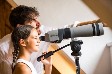 Girl looks through telescope and father explains something to her | © krimmler-wasserwelten.at/Stabentheiner